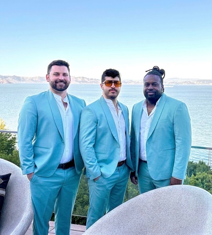 The three Spotlight founders in matching turquoise suits overlooking the bay